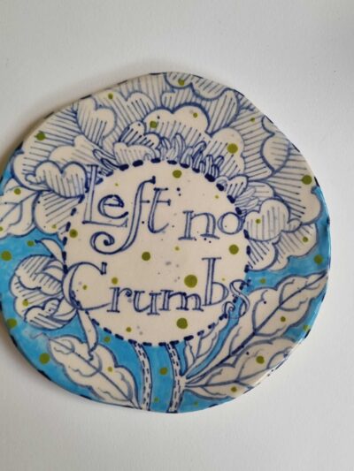 left no crumbs platter. Coloured underglazes on midfire white clay. Slab form. Clear glaze. Has attached hanging device