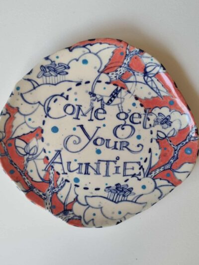 come get your auntie platter. Coloured underglazes on midfire white clay. Slab form. Clear glaze. Has attached hanging device